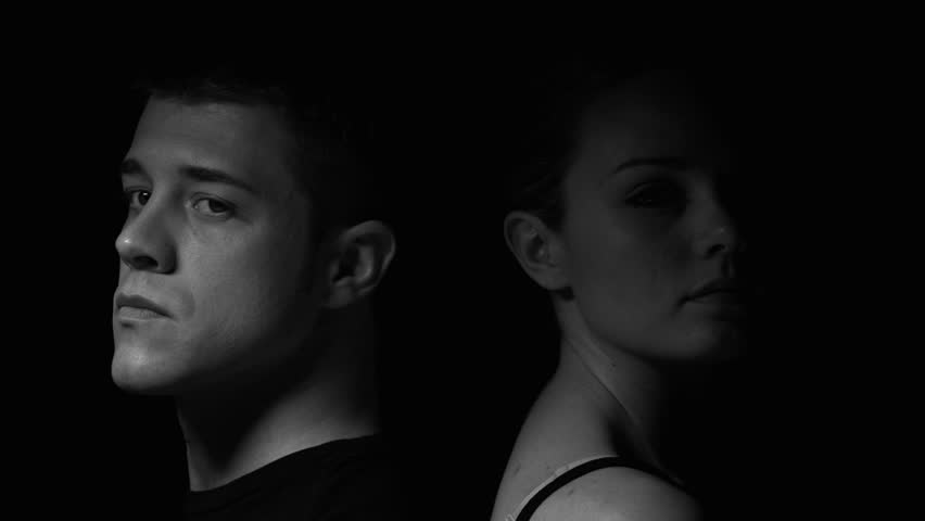 Man and woman sitting back to back in black and white. Experimental lighting.