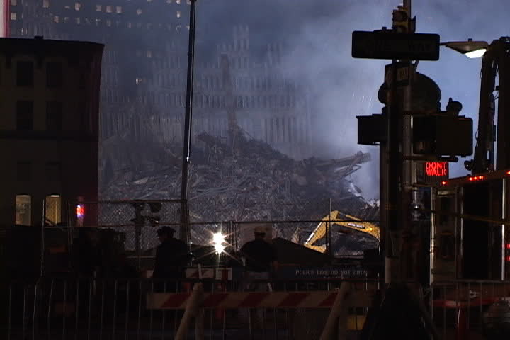 NEW YORK CITY - SEPTEMBER 28, 2001: Smoke rising from rubble at World Trade Center site. Passing vehicles and emergency workers in foreground.