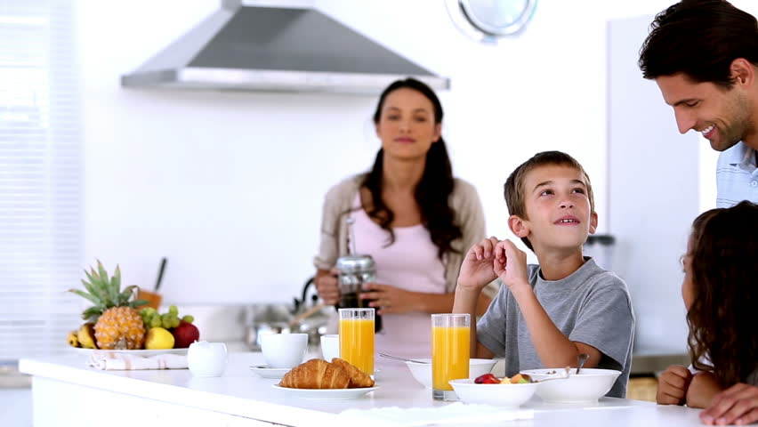Mother pouring coffee at family breakfast in the kitchen