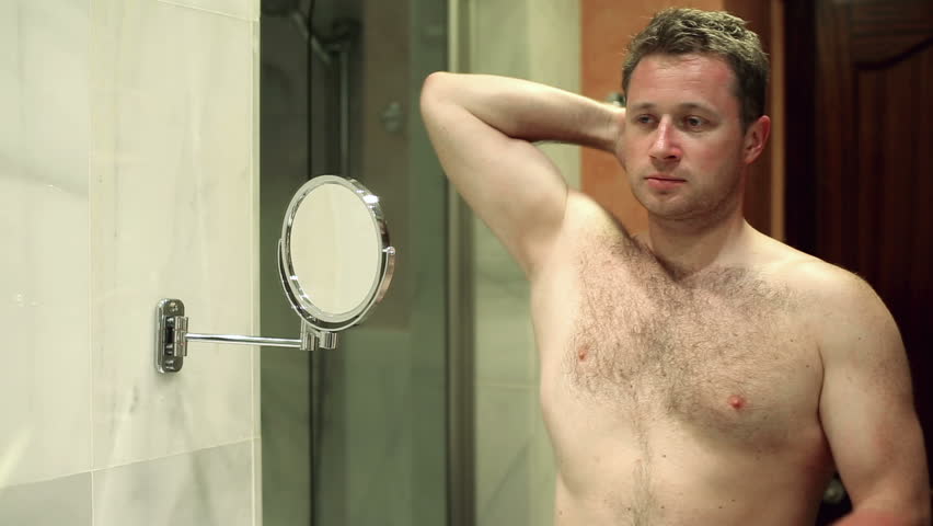 Man takes care of his hygiene by applying deodorant to his armpit
