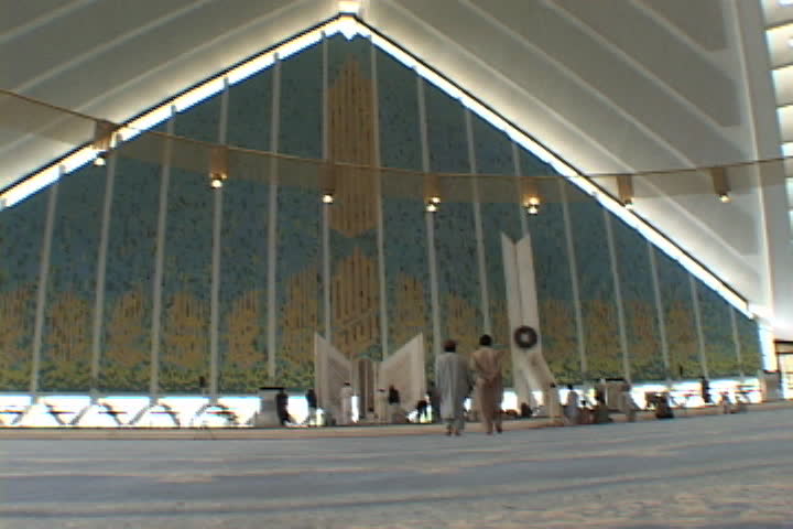 ISLAMABAD, PAKISTAN - NOVEMBER 01, 2001: Men enter empty prayer hall of Faisal Mosque, and walk towards huge replica of the Koran.