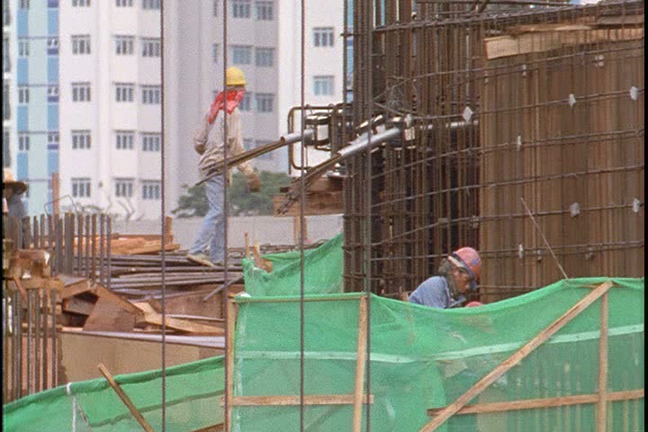 KUALA LUMPUR - OCTOBER 25, 1999: Kuala Lumpur construction site; CU big red hook lifts bundle of rods. CU rods as they're flying across site, then lowered by big red crane hook.