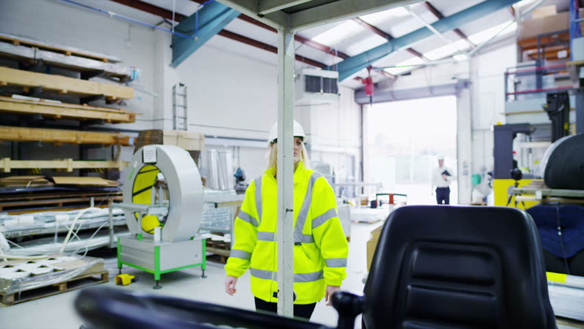 A male forklift truck driver arrives on shift in a factory or warehouse to take over from his female co-worker. 