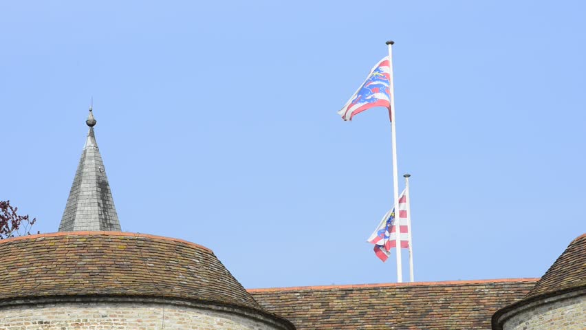 Two waving flags of the Bruges city on top of the Gentpoort gates