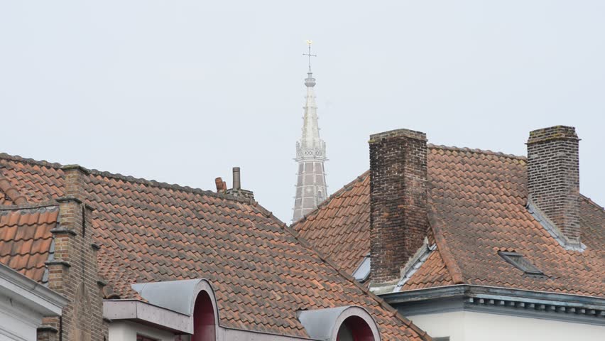 Tiled roofs and spire of Church of Our Lady in Bruges, Belgium. Zoom out from and zoom in to the spire of Church of Our Lady.