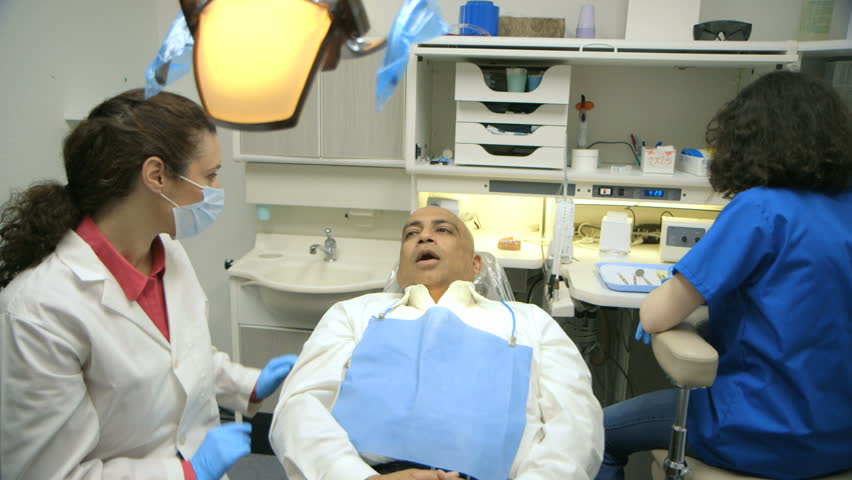 A good dental checkup results in big smiles for a patient as well as the dentist and a young intern assisting her.