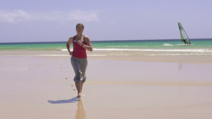 Young woman jogging on beautiful beach
