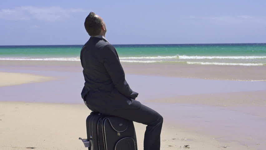 Businessman with suitcase relaxing on beautiful exotic beach
