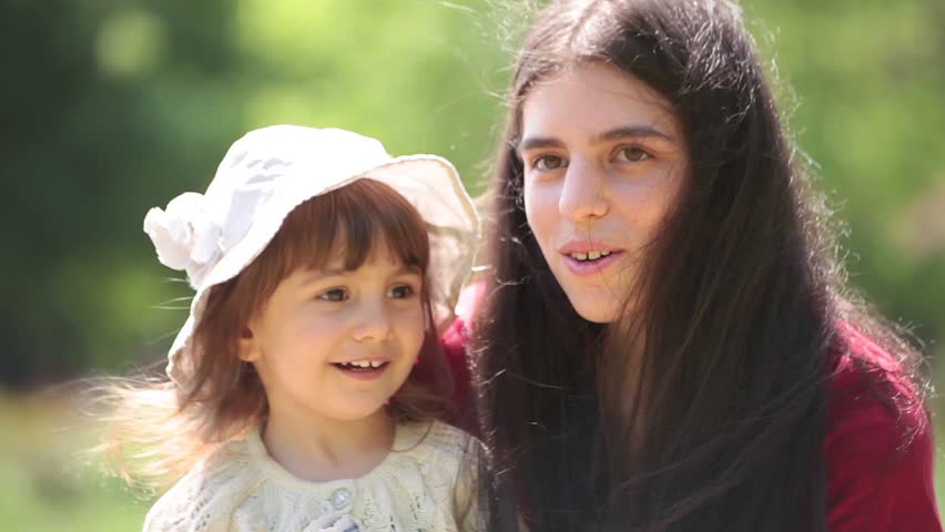 Young adult mother and daughter sing and hug together.
