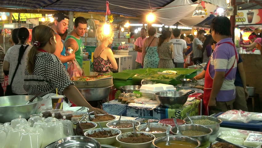 PHUKET, THAILAND - 11 MAY 2013 - Street food market in Phuket, Thailand. People pass trough food vendors and tourists look at the food stall.