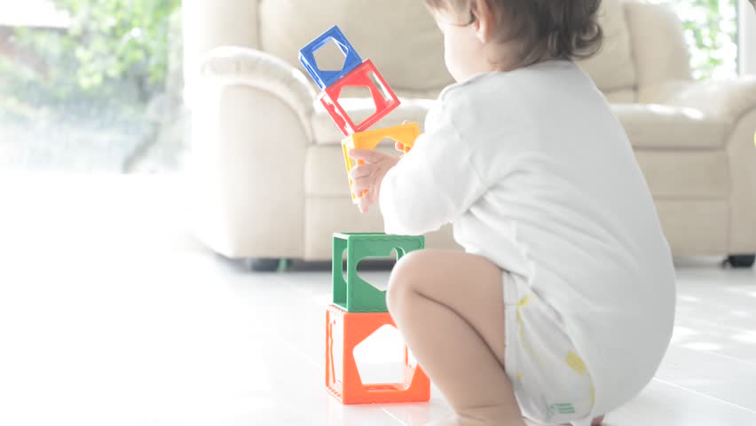 Little cute boy playing at home with toy cubes