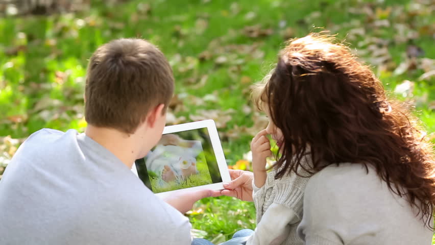 Happy family using tablet PC outdoors in autumn park