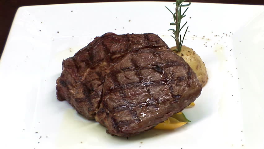 RIB EYE STEAK. Twelve oz grilled rib eye steak with grilled potatoes on a white dish. 
