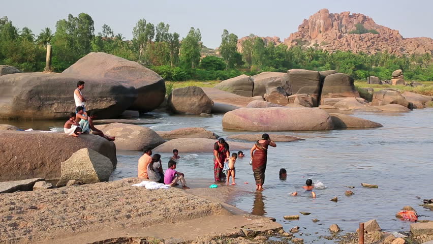 HAMPI, KARNATAKA, INDIA - APRIL 2013: People bathing in mountain river