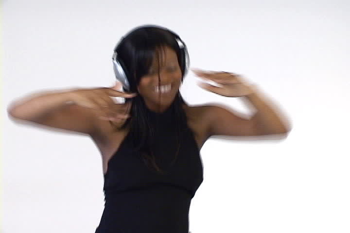 A young African American woman with headphones on dances to the beat.