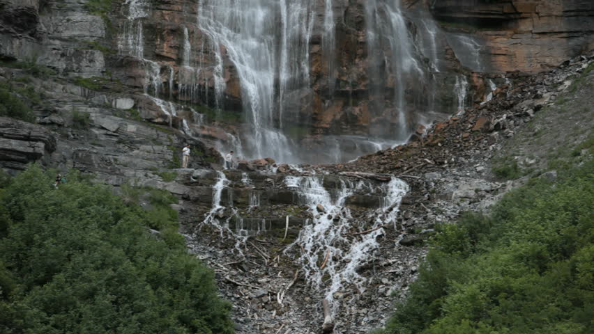 Bridal Vail Falls on Provo River in Utah. Two hikers cross at bottom.  Wasatch Mountains. Central Utah near Salt Lake City, Provo and Orem. Summer recreation and activity. 