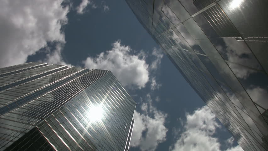Office towers reflect sun and clouds. Timelapse shot.
