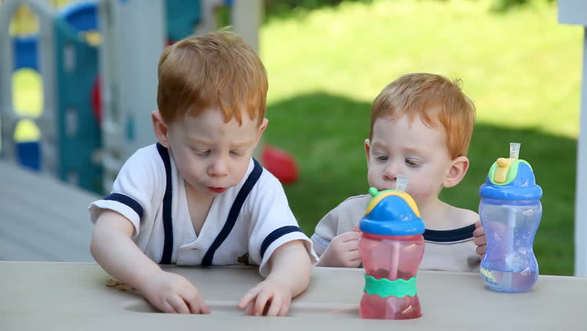 Twin babies snacking in garden