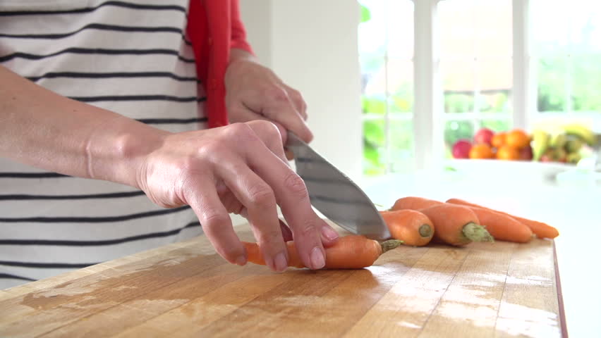 Kitchen Counter Close Up close up of middle aged woman cutting and peeling carrots on Kitchen Counter Close Up close up of middle aged woman cutting and peeling carrots on