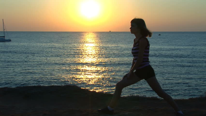 Girl does stretches against the sea during a decline. The yacht by floats.