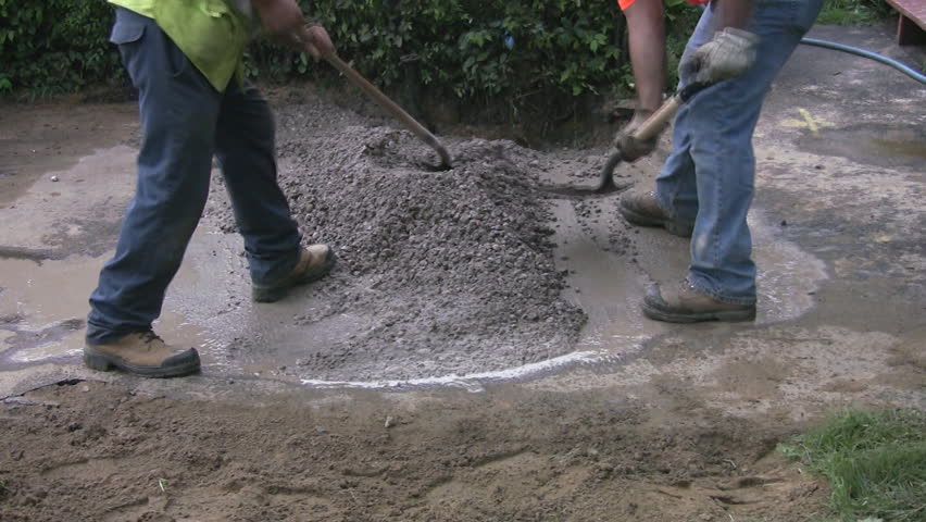 Workers shovel cement into a hole.  Toronto, Ontario, Canada.