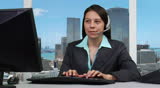 Female supervisor at PC talking on headset  - skyline background