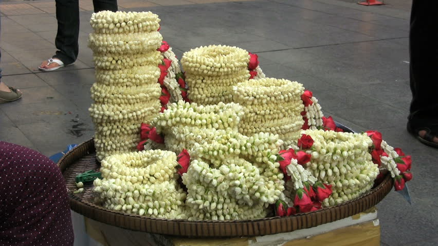 A Thai lady selling flower garlands on the sidewalk in Bangkok, Thailand.