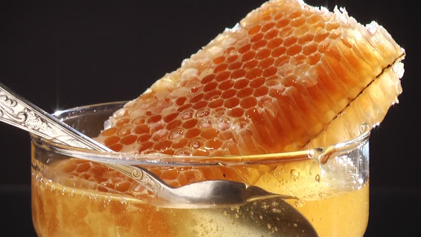 Closeup of honey pouring on the honeycombs