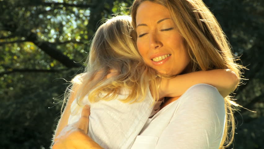 Attractive mother tenderly holding her daughter while outdoors on a summers day