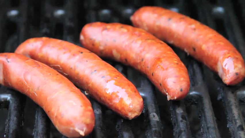 Turning sausages on a gas grill