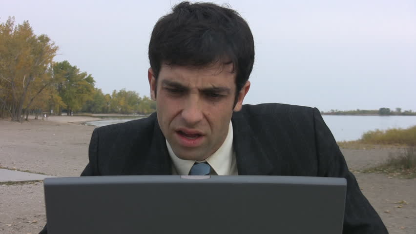 Laptop distress. A young businessman gets stressed out by bad news on his laptop. 