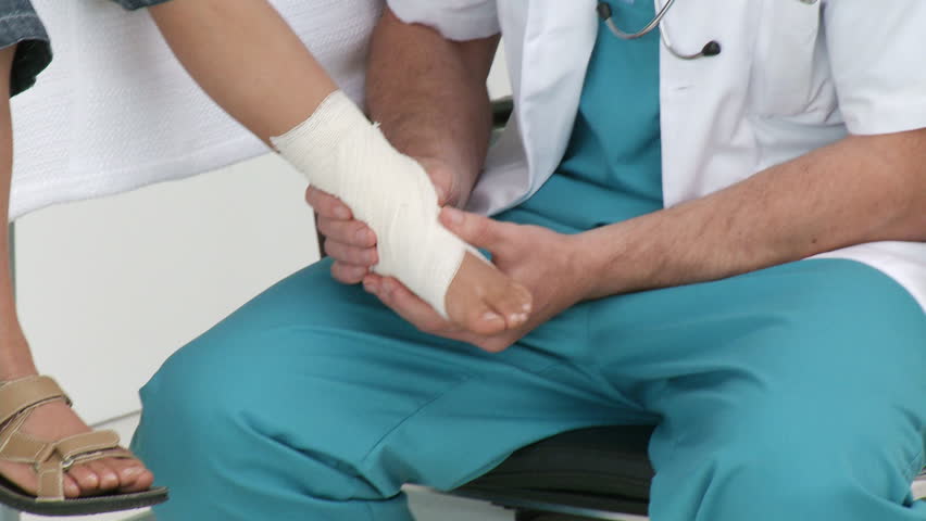 Doctor bandaging a patient's foot who is with his father in medical office. Concept of healthcare. Footage in high definition