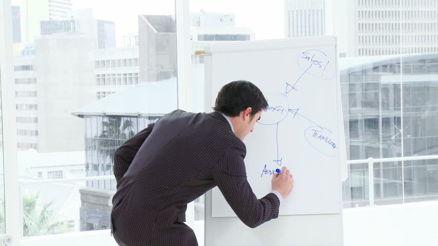 Active young businessman writing in a whiteboard a business plan in a meeting. Footage in high definition