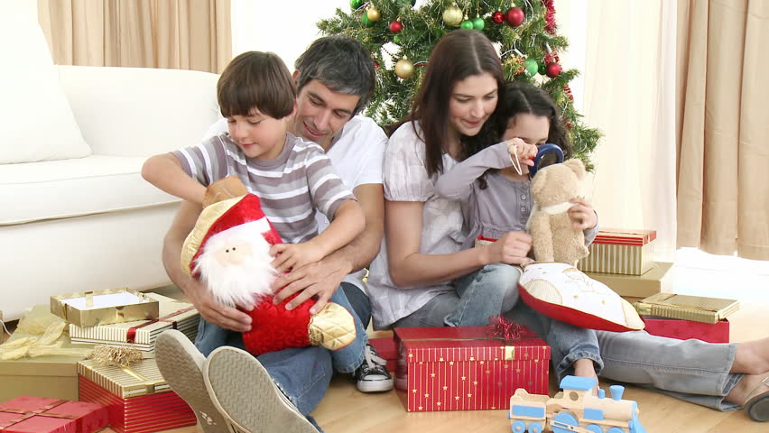 Parents and children opening Christmas presents at home. Footage in high definition