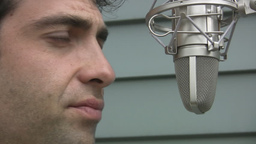 Man talks to microphone. Closeup. Man talking into a professional condenser microphone. 