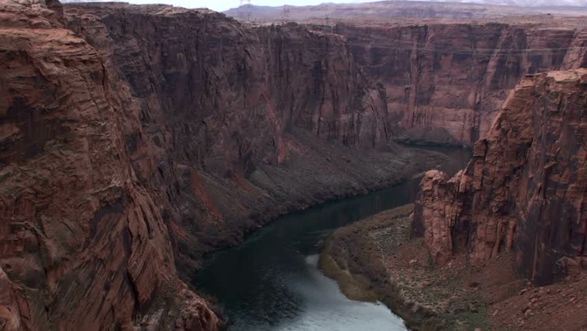 Pan down Colorado River, through canyon rock, leads to Glen Canyon Dam. 1920x1080