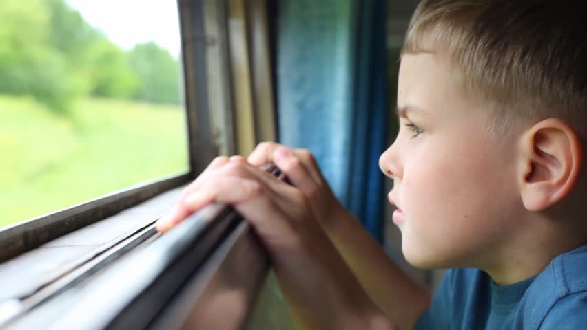 boy looking on nature from moving railway carriage 