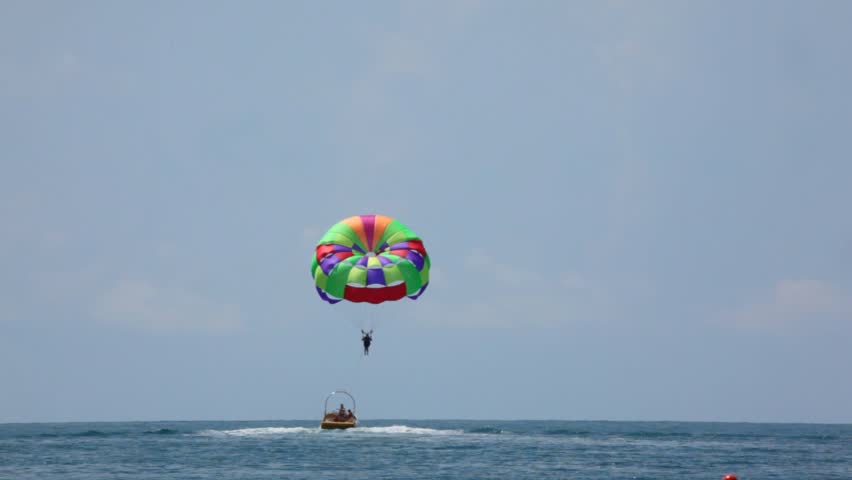 parasailing on sea, cutter have man with parachute in tow 