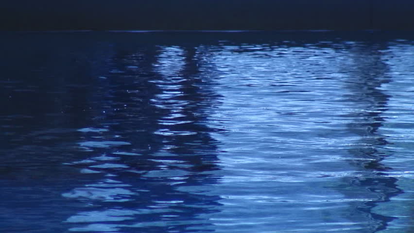 Diver breaking surface of swimming pool water