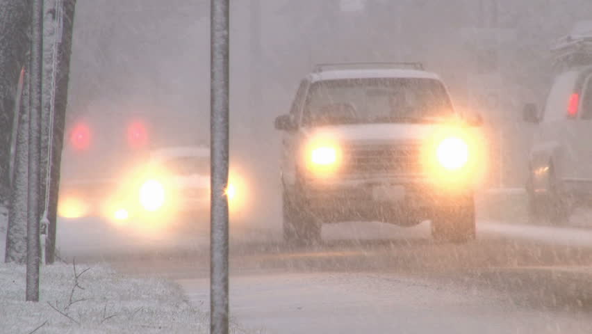 Blizzard conditions with vehicles driving on snow filled roads in Portland, Oregon.