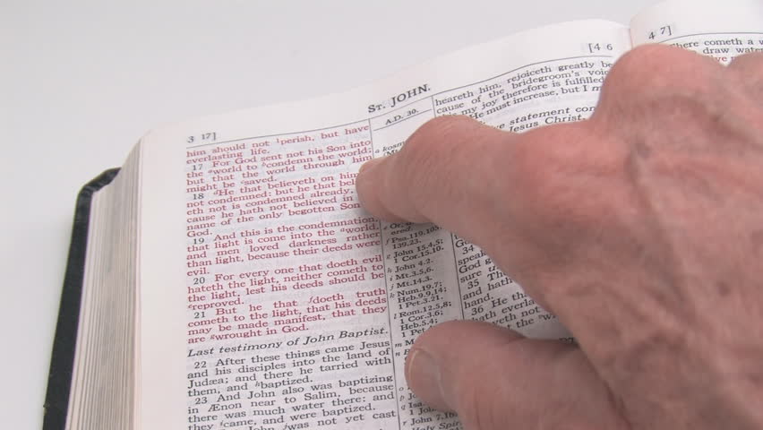 A man moves his finger moves across the page as he reads the Gospel of John.