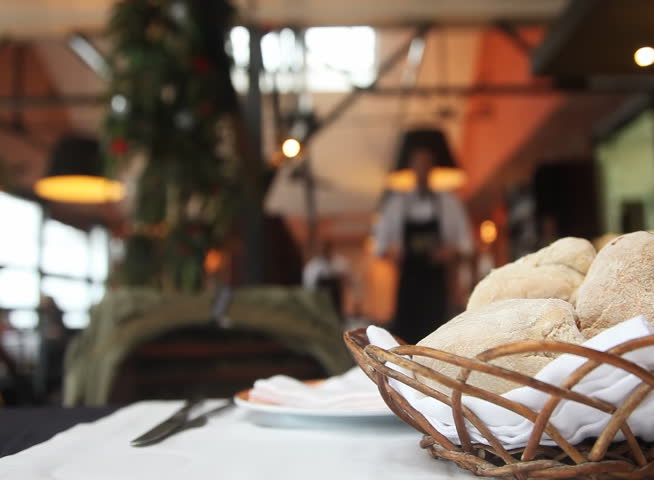 Table setting in restaurant with bread, empty glass and waiters 