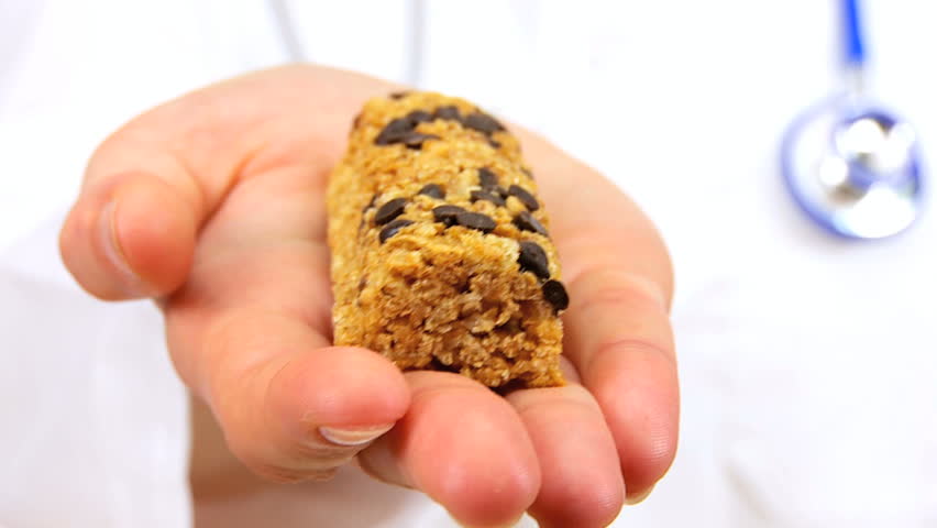 Doctor in white coat offering a low calorie fruit & cereal bar as a healthy food snack