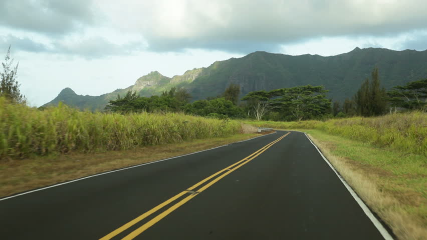 Driving point-of-view on a rural road on Kauai, Hawaii, near Puhi, with the Haupu mountain range in the background.