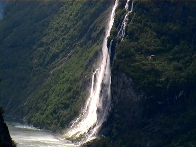 Beautiful aerial view of Geiranger fjord, Norway. With Seven Sisters Waterfall and snow capped mountains. Taken from Eagles Road with camera zooming out.