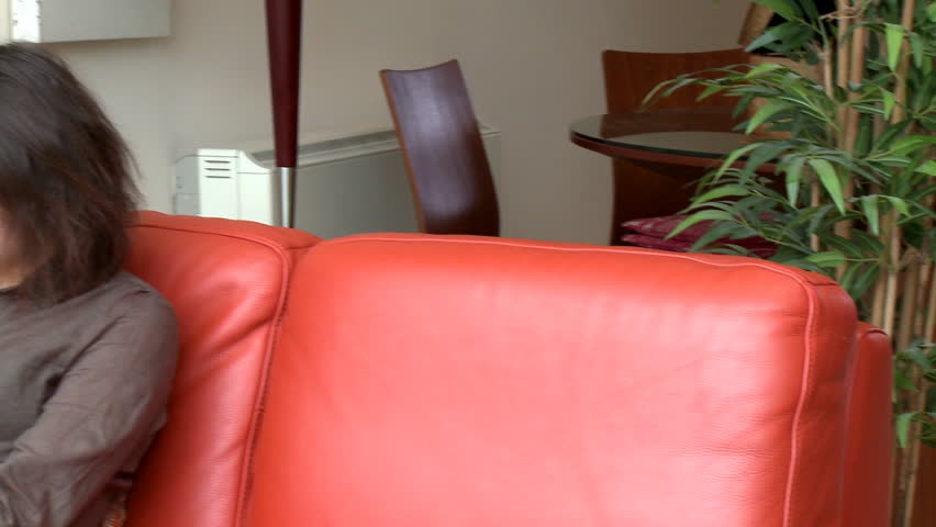 Intellectual woman reading a magazine sitting on sofa