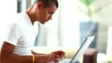 Happy young man working on laptop - Indoor