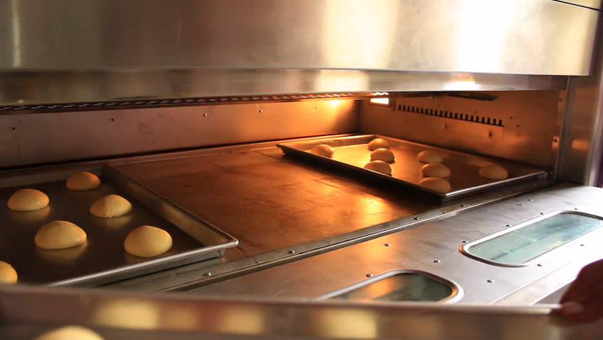 Placing bread rolls into the oven 