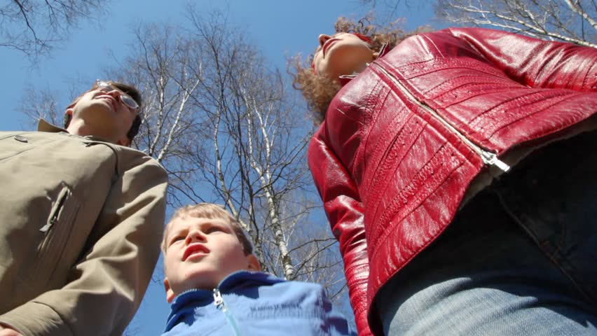 family of three admires the scenery in spring park, down-top view 