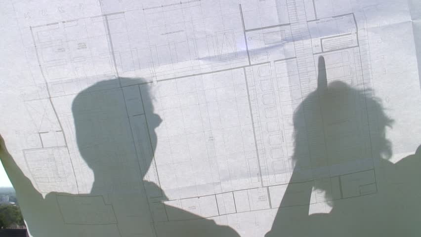 HD 1080i: Shadows of two people on a construction plan discussing. Tripod.
